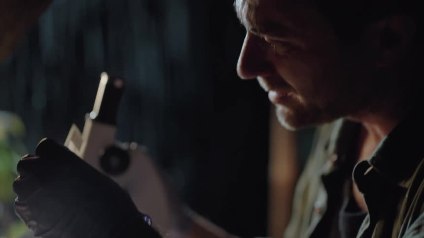 A man is looking at slides as he sits in front of a microscope