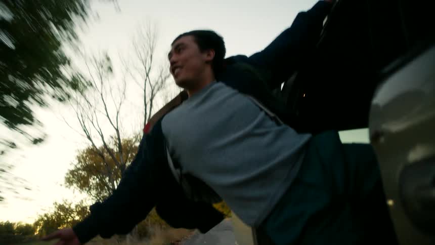 A person hanging out of a van sliding door wind surfing while the car drives