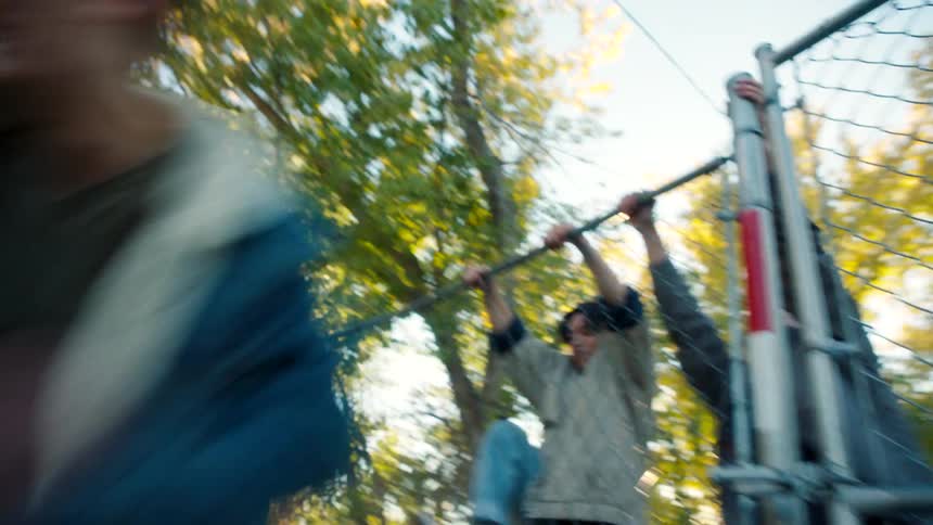 Group of four young men and friends jumping over a fence
