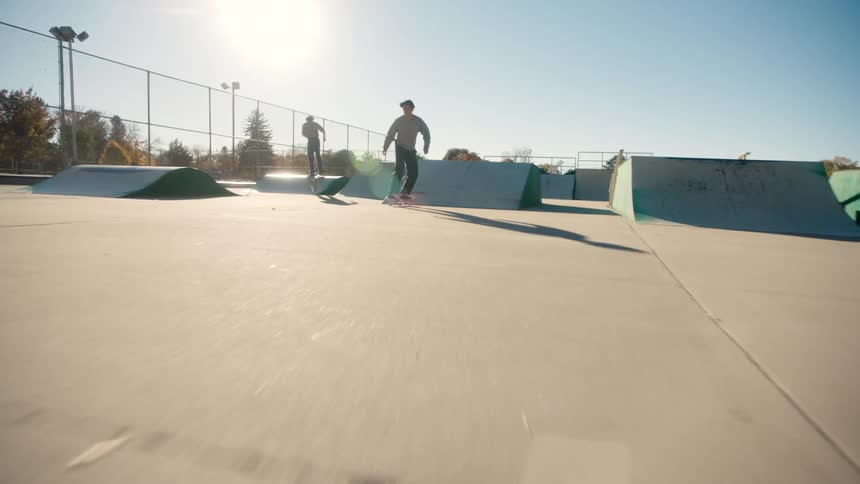 A teenager speeds by in the park on his skateboard