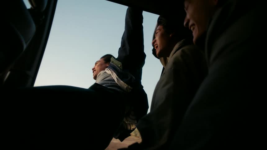 A teenager is hanging out of the speeding vehicle