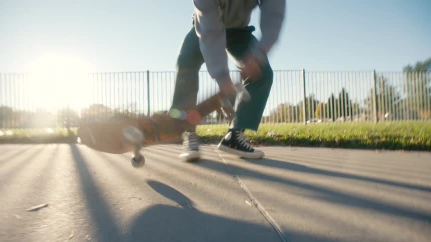Angry teenager aggressivley jumping on skateboard breaking it and tossing it over the fence