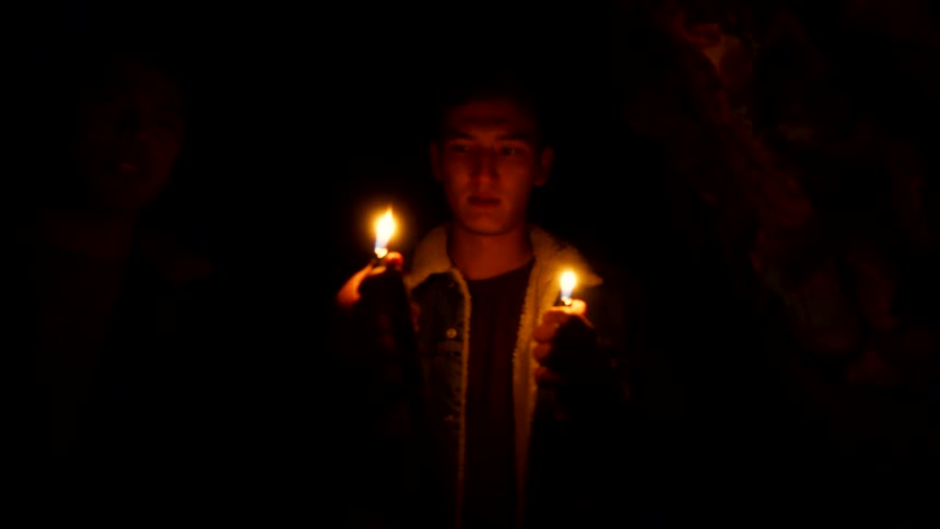 Teenagers light their lighters in the cave