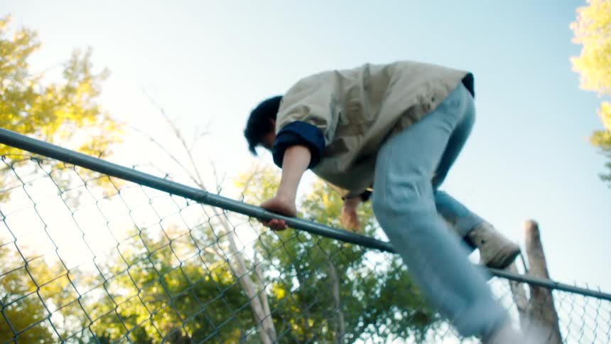 Teenagers jump the fence together