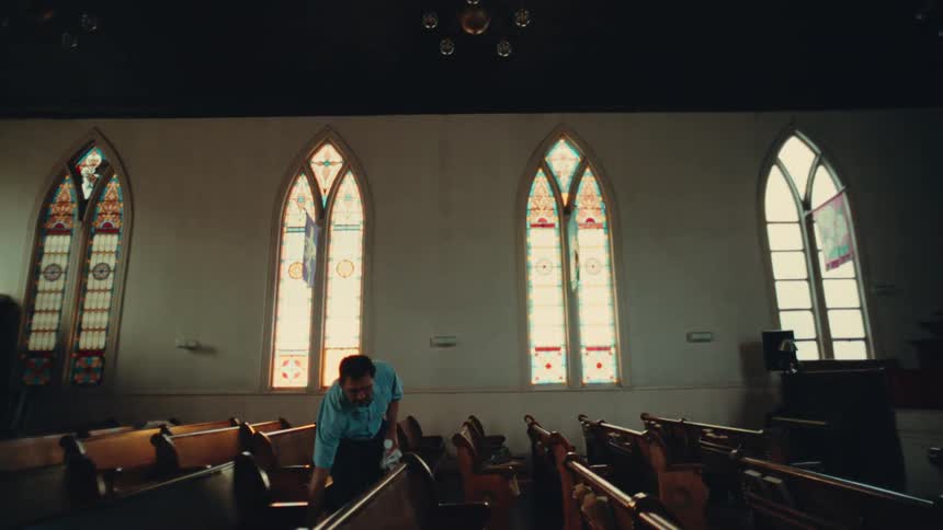 A man walks through the church cleaning the pews