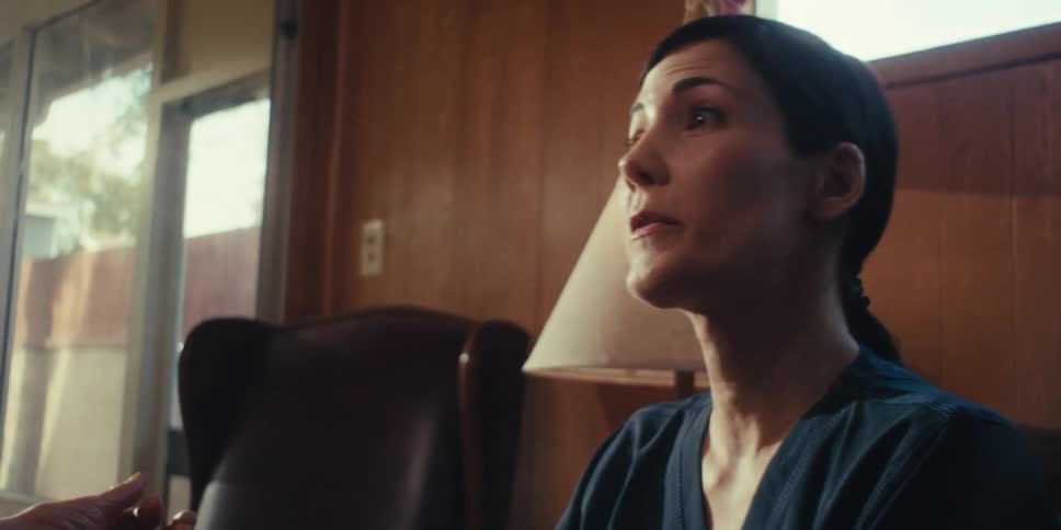 A woman is sitting on a couch and talking to someone