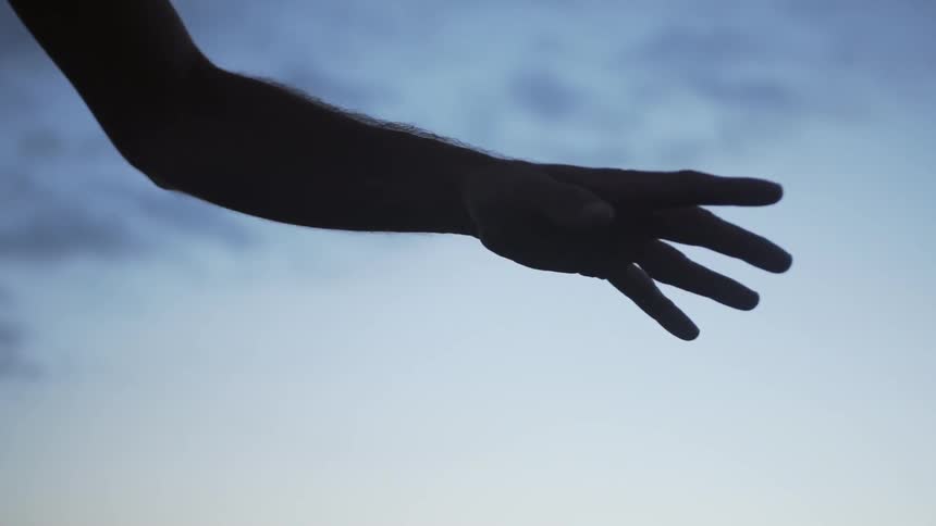 A man's hand is curving and his fingers moving as he dances