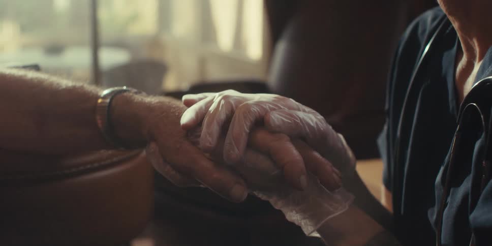 A patient is holding a patients hand and rubbing it