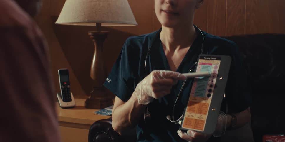 Nurse showing a device while pointing it to an elderly man