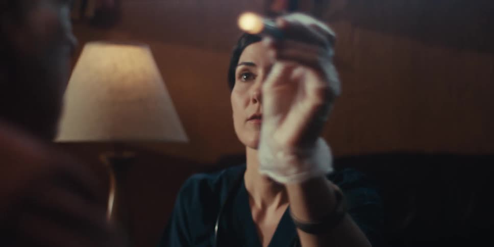 A woman tests a mans eyes with a pen light