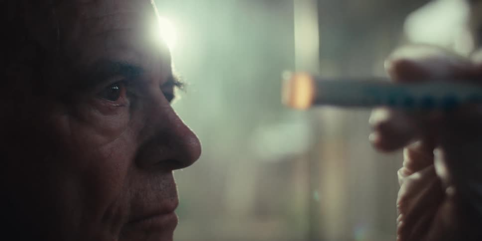 Elderly man follows the light while being given an eye exam