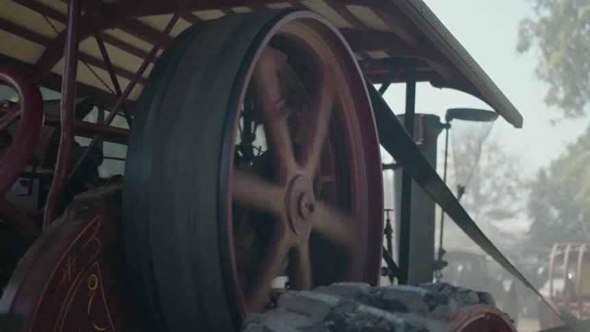 The engine is spinning a large wheel with a belt around it