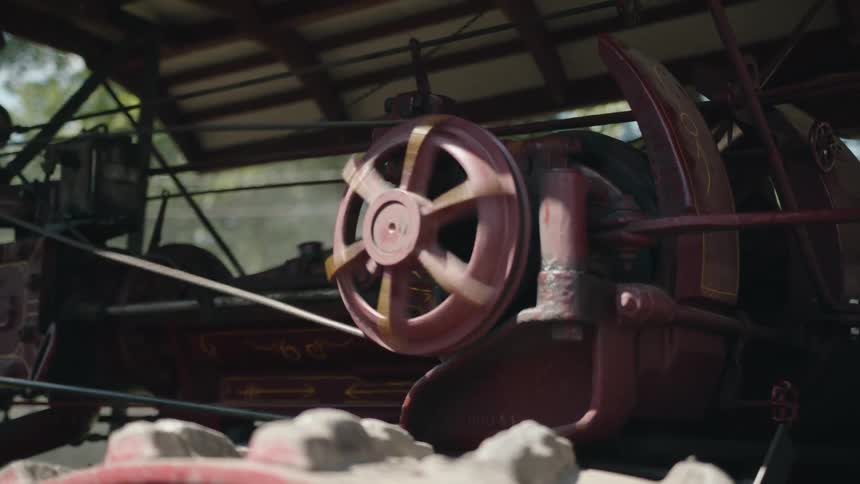 A man uses a tool on the large machine