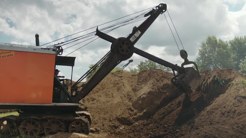 Excavator removing dirt from side of a slope