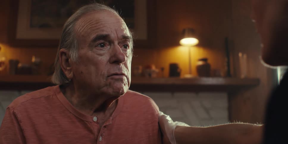 A footage of an elderly man having a conversation with a person indoor