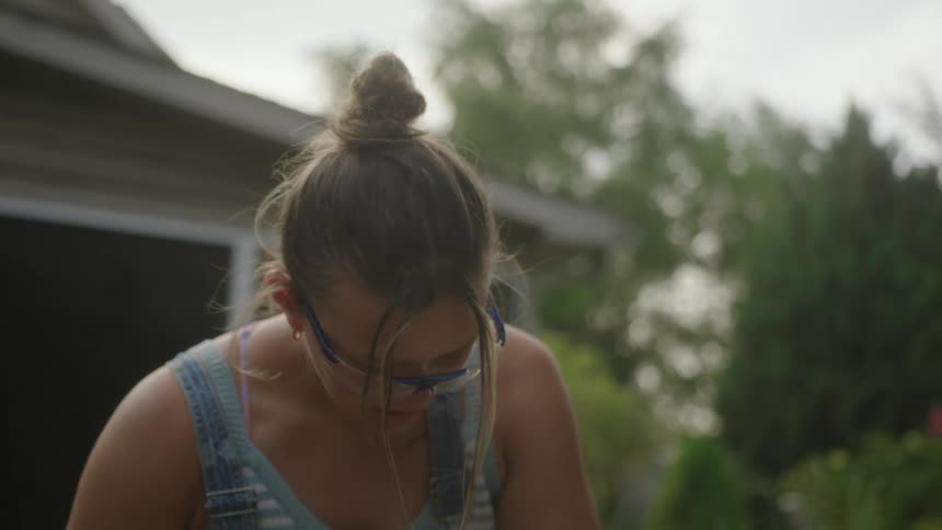 The girl is working on something in her yard
