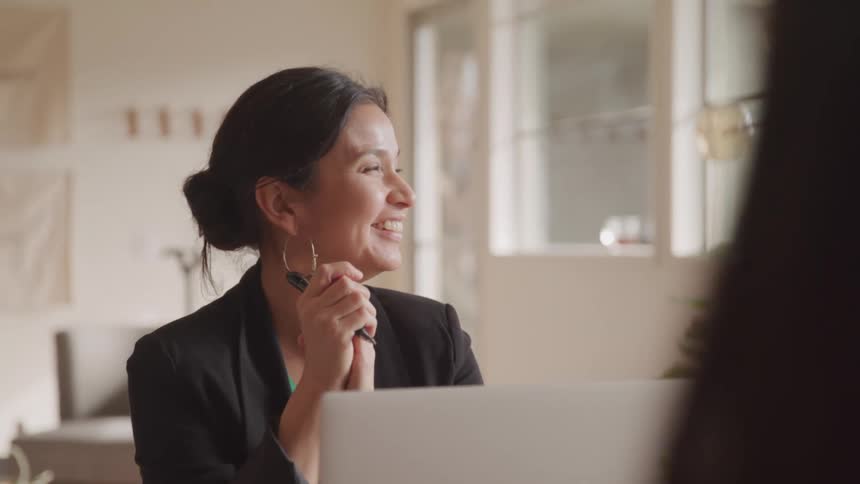 A woman is talking by her laptop