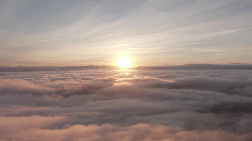 The sun is setting in the horizon above the cumulus clouds