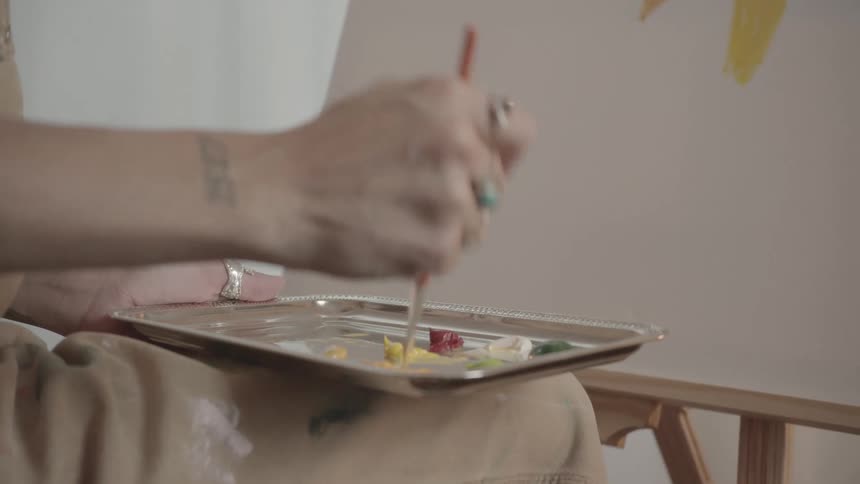 A woman is mixing paint together while making art
