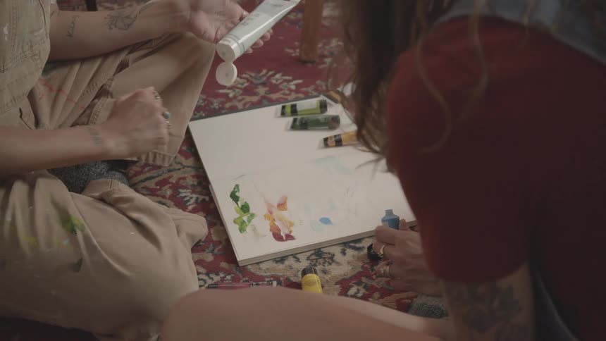 Two women are finger painting together