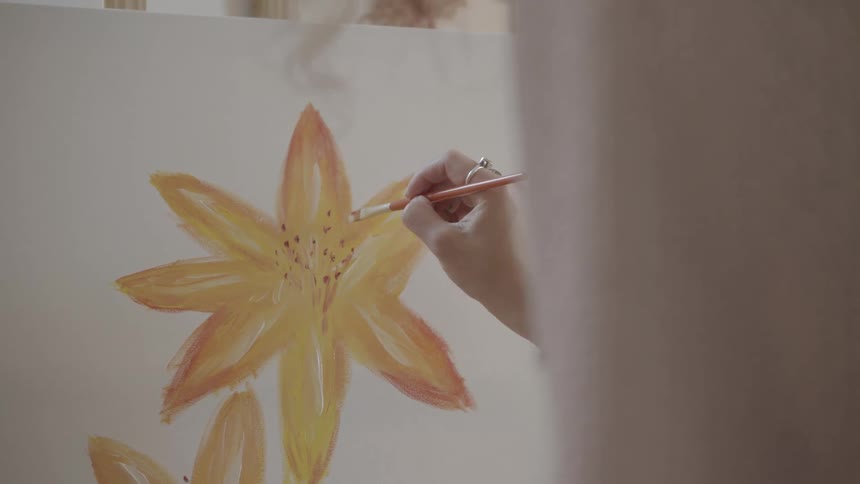 A woman is painting yellow flowers on a canvas