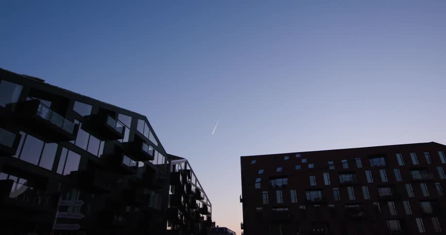 Two modern apartment buildings stand silhouetted against a clear twilight sky