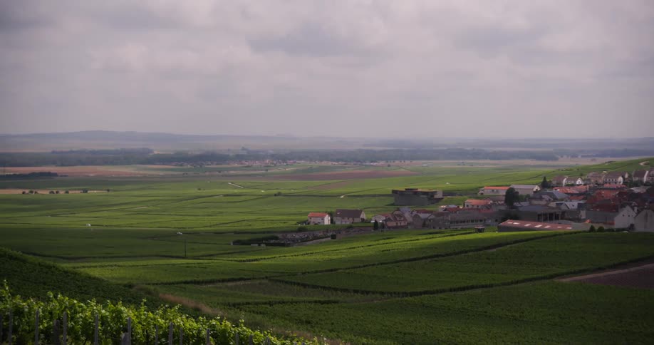 Vehicle drives away from a rural town in the green countryside on an overcast day