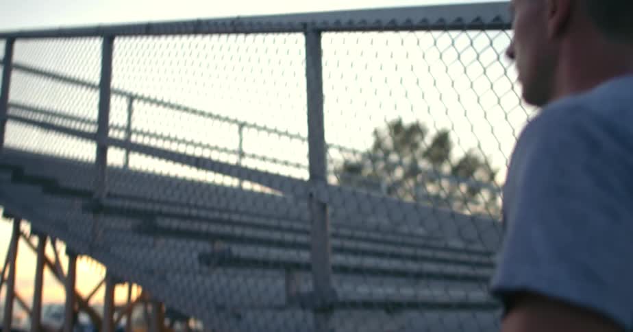 A man walks off a field and past the bleacher seats