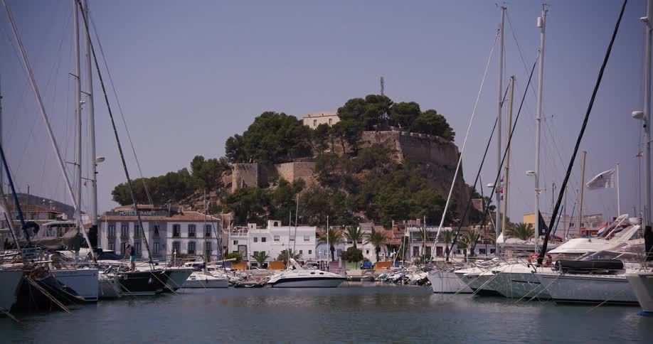 A man walks around a sailboat that is docked at a marina at a castle