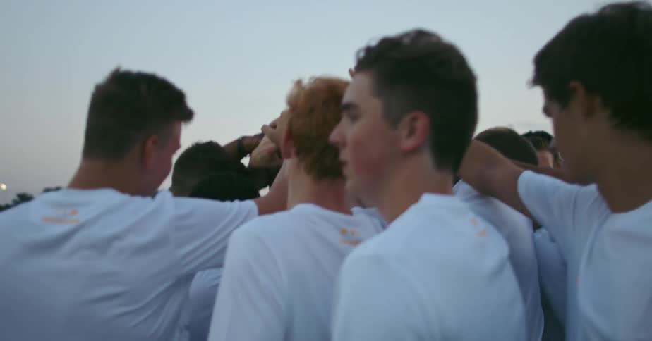 A soccer team is huddled prior to a game on a field at dusk