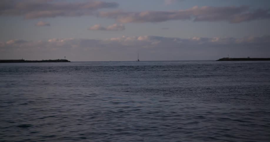 A calm dark expanse of water under a dusky sky with scattered clouds possibly at twilight