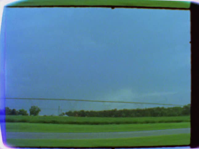 Cars travel on the road before this long green field