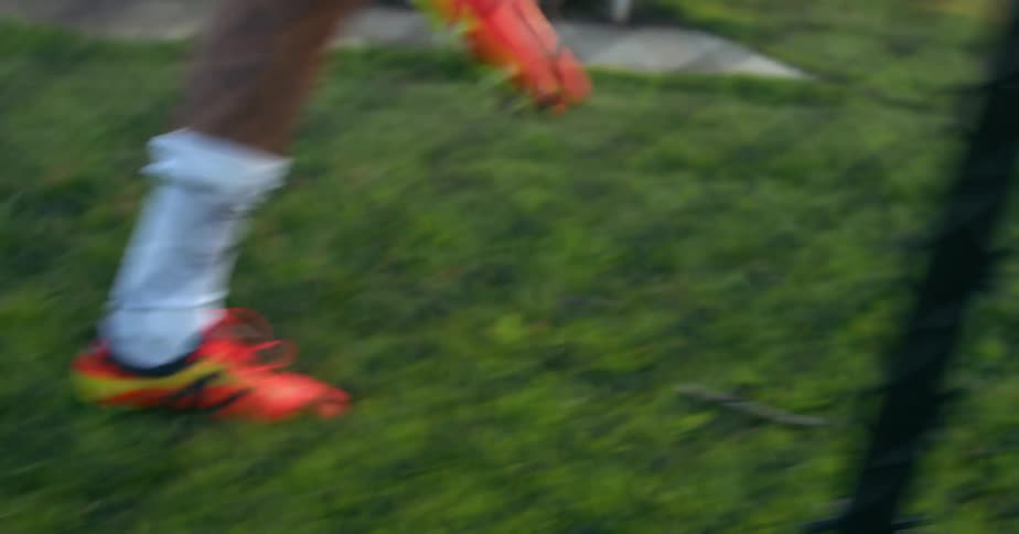 An athlete wearing cleats warms up on a grassy field