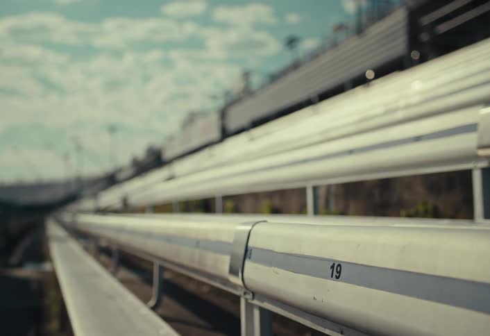 Numbered metal bleachers in an outdoor stadium are shown in closeup under a partly cloudy sky