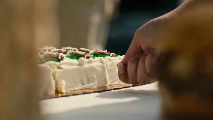 Cutting the corner slice off a sheet cake with a plastic knife