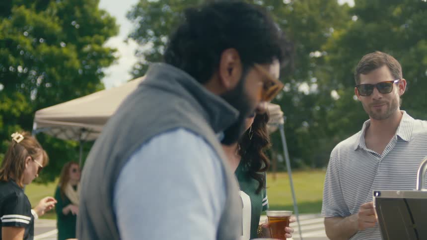 Friends with glasses of beer talking outdoors at a barbecue