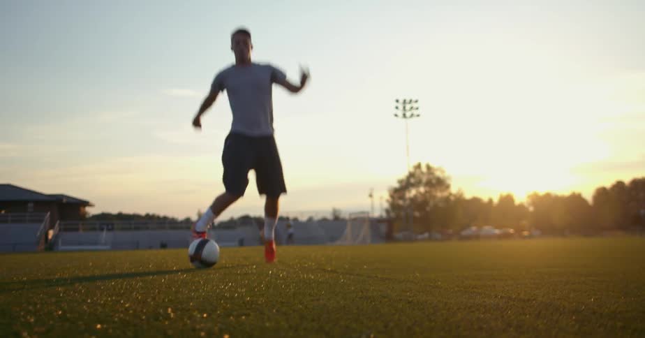 A man dribbles a soccer ball across a field