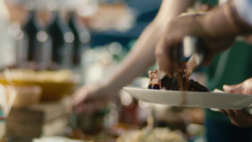 People are putting food on their plates from the table outside