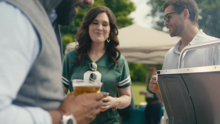 Flipping burgers on a grill while hanging out with friends having beer