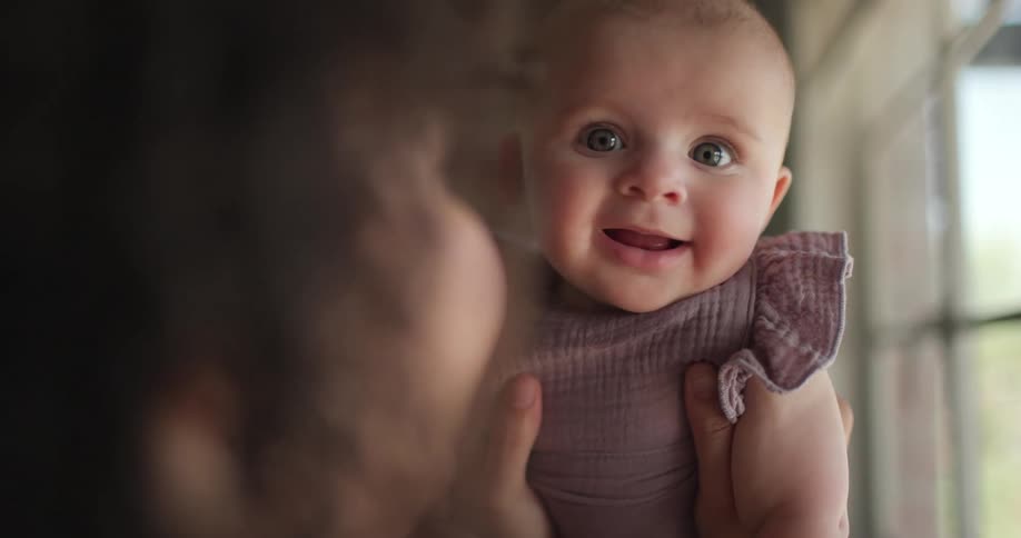 A mother is holding up her happy baby