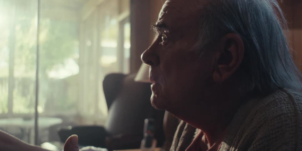 A closeup of an elderly mans head as he talks to someone at home on a sunny day