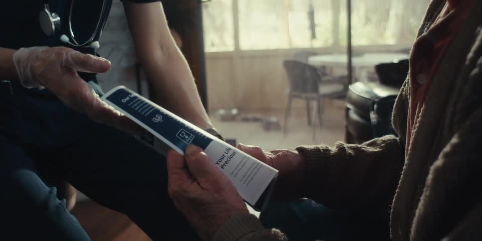 Nurse handing and explaining a medical pamphlet to a dejected elderly man