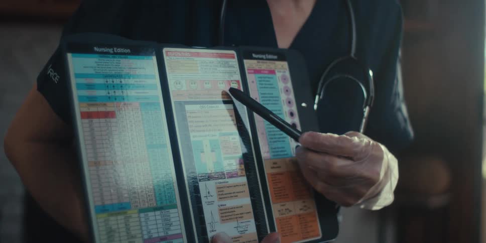 A closeup of a doctor holding a medical chart as a patient points to it with their finger