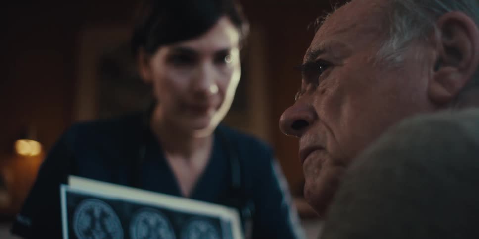A nurse is showing her patient an x ray print out