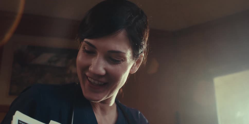 The nurse nods her head and smiles while talking