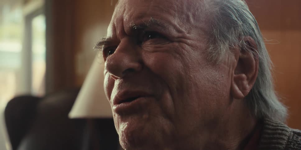 A closeup of an elderly mans face as he listens intently to someone at home on a bright sunny day