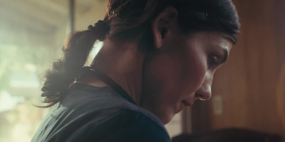 A closeup profile of a nurse with a stethoscope over her shoulders attentively listening to someone at home on a sunny day