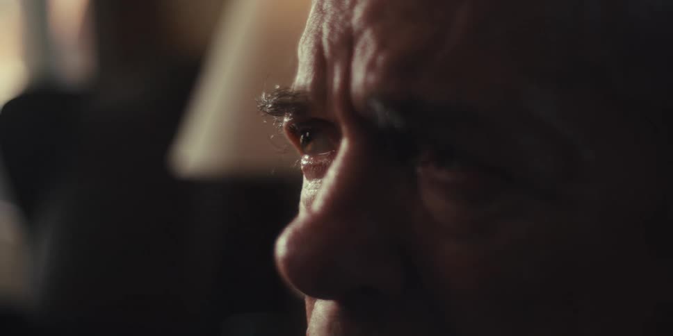 A closeup shows the forehead and furrowed brow of an elderly man with a worried or sad expression at home