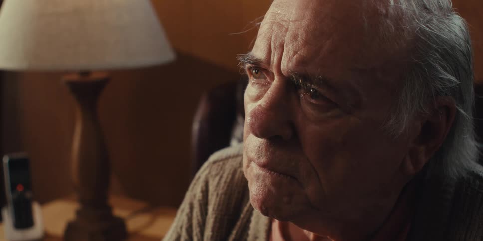 A closeup of an elderly mans face as he looks up at someone with an attentive expression