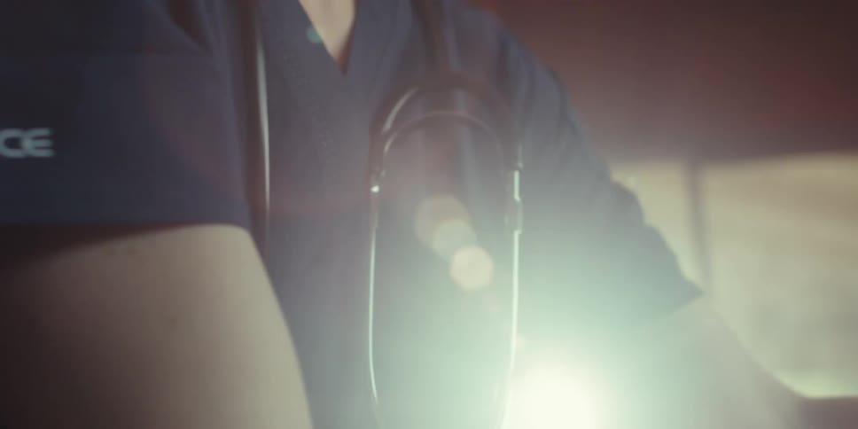 A medical professional wearing a stethoscope moves around in a room